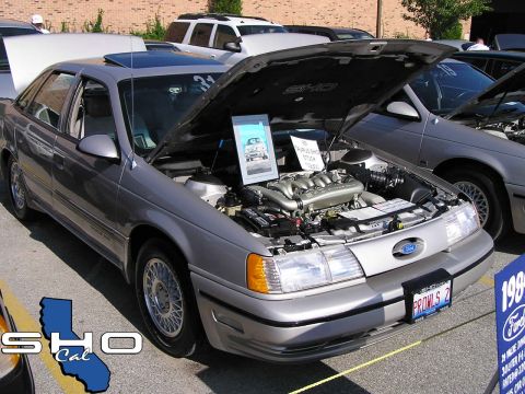 1993 Ford Taurus - 1993 Ford Taurus SHO at a car show, engine displayed. Other vehicles visible in background.