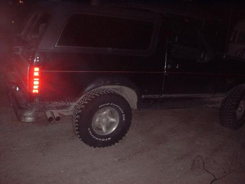 1993 Ford Bronco - This black SUV is viewed from the rear, showing its vertical taillights and off-road tires.