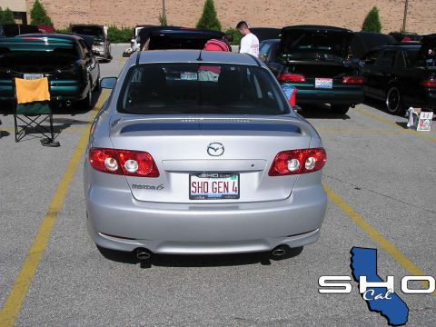1993 Ford Taurus - A silver Mazda 6 is parked in a lot with other vehicles, showing its rear end and license plate.