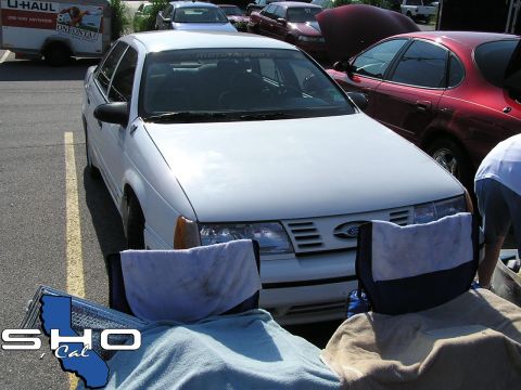 1993 Ford Taurus - A white 1992 Ford Taurus sedan is parked in a lot, with other vehicles visible in the background.