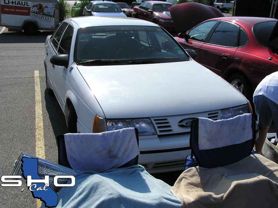 White 1992 Ford Taurus sedan, front view, parked in lot with other cars