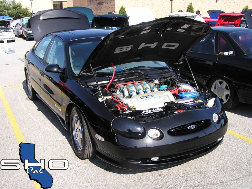 Black Ford Taurus SHO with hood open, showing V8 engine and 'SHO' badging on fender and hood