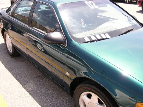 1993 Ford Taurus - Side profile of a 1993 Ford Taurus sedan, racing seats visible through the window.