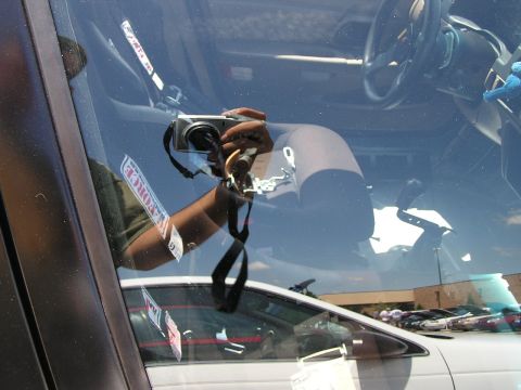 1993 Ford Taurus - A reflection shows the interior of a car, including the steering wheel and seats, with other vehicles visible outside.