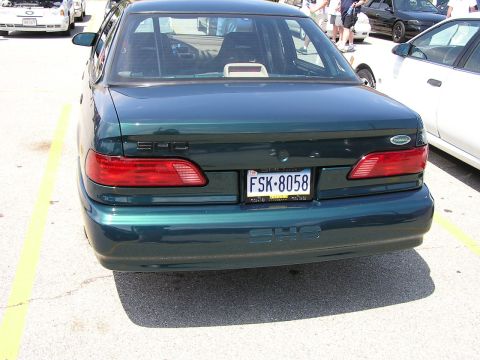 1993 Ford Taurus - The rear of a dark green sedan, identified as a 1992 model by its body style, is visible in a parking lot.