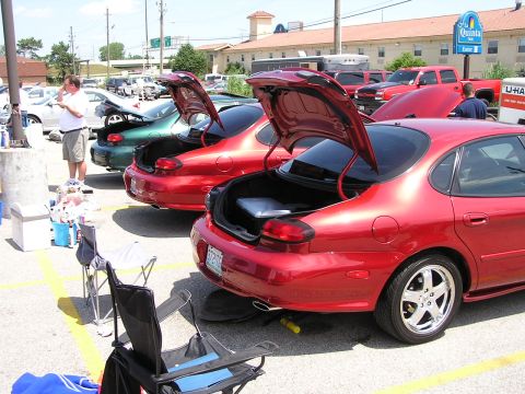 1993 Ford Taurus - Several Ford Taurus sedans are gathered, their trunks open, in a parking lot on a sunny day.