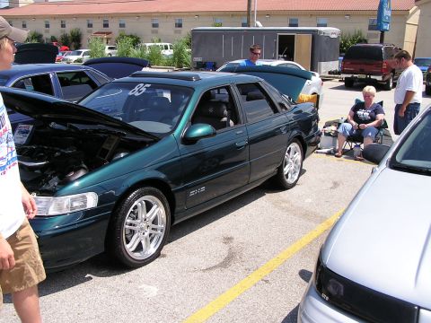 1993 Ford Taurus - A green 1993 Ford Taurus sedan is displayed with its hood open at an outdoor car event.