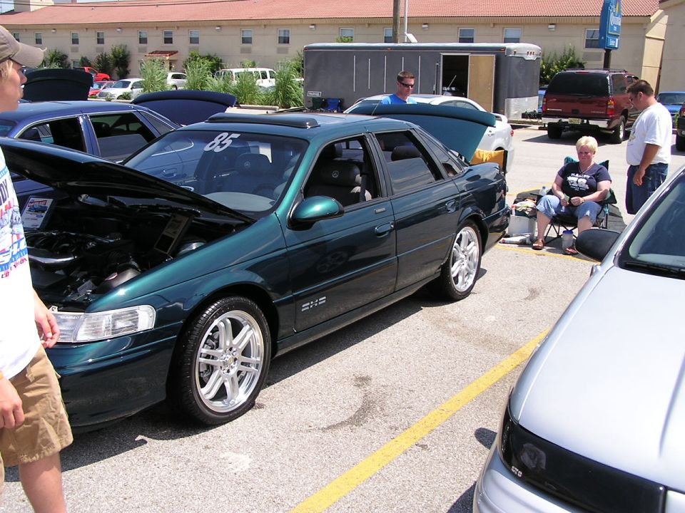 Green 1993 Ford Taurus sedan with hood open, custom wheels, sunroof, and a racing number '85' on the windshield
