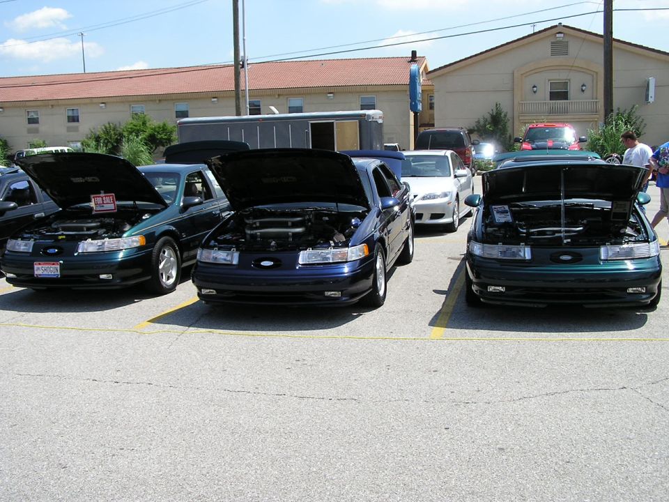 Three 1993 Ford Taurus sedans parked with hoods open, one has a 'For Sale' sign