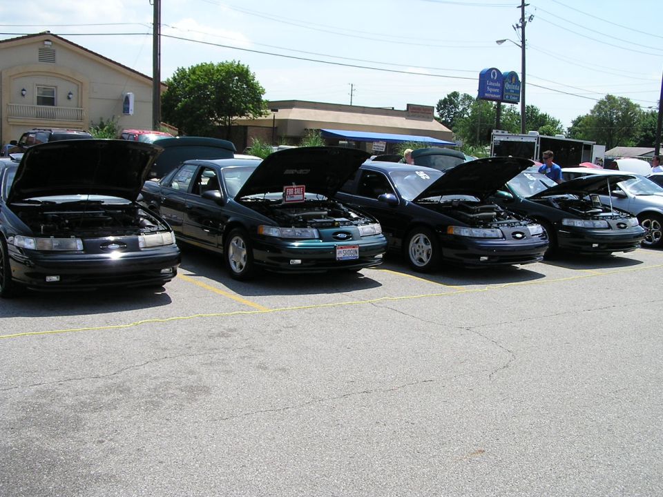 Four Ford Taurus sedans parked in a row with hoods open