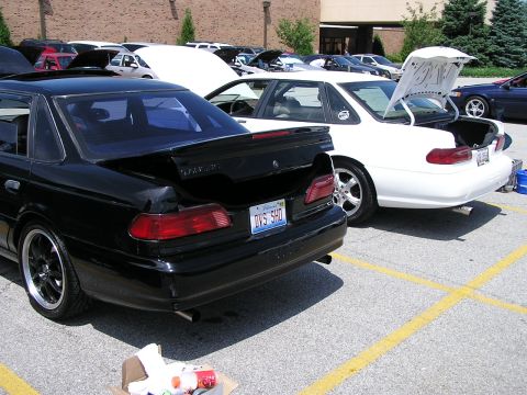 1993 Ford Taurus - Two Ford Tauruses are parked side-by-side with their trunks open at an outdoor event.