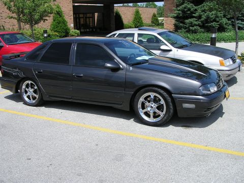1993 Ford Taurus - This modified sedan, likely a mid-1990s model, is parked next to another vehicle.