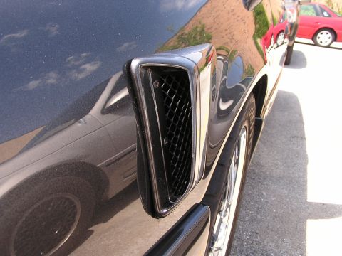 1993 Ford Taurus - Side vent detail on a dark vehicle, with another car parked nearby.