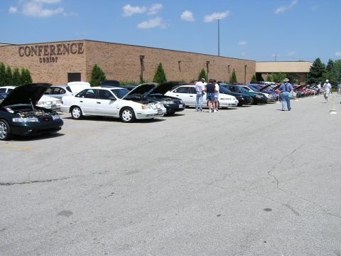 1993 Ford Taurus - A line of cars are parked in front of a conference center on a sunny day.