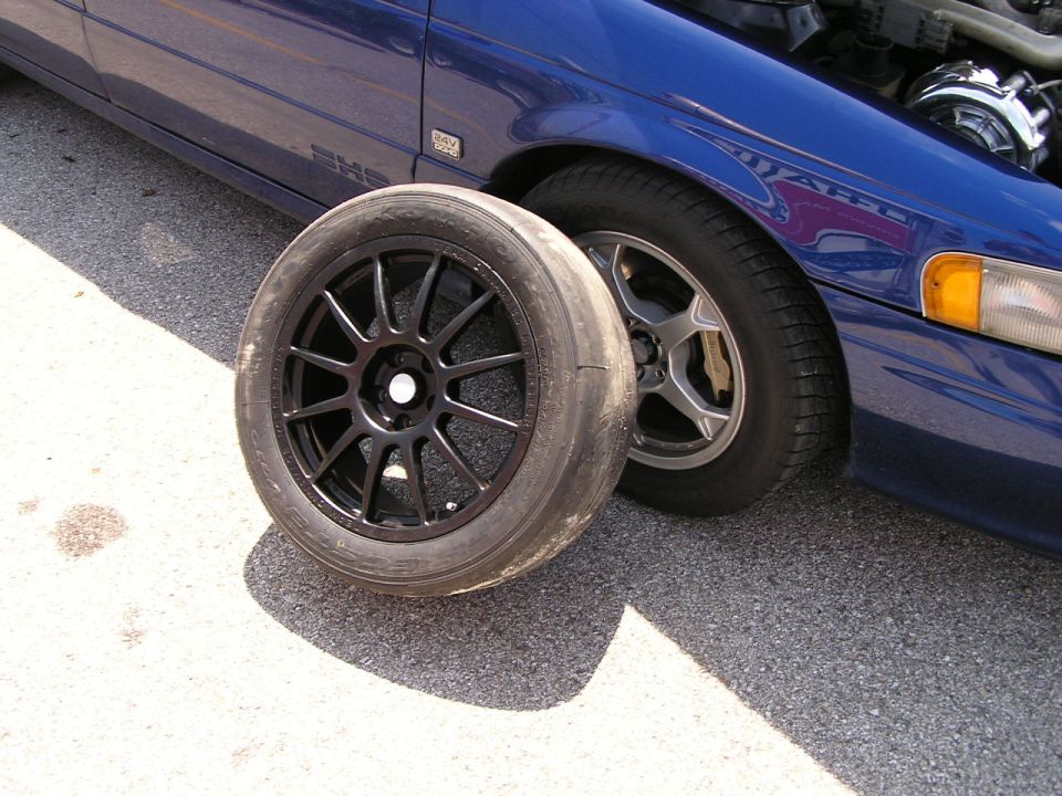 Blue 1993 Ford Taurus with a black aftermarket wheel and tire in front of the driver's side wheel