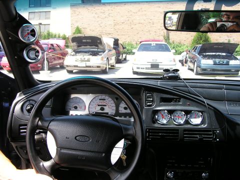 1993 Ford Taurus - The interior of a 1993 Ford Taurus is visible, with a reflection of the photographer in the rearview mirror and other cars outside.