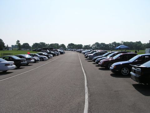 1993 Ford Taurus - A large gathering of vehicles are parked in an outdoor lot on a clear day.