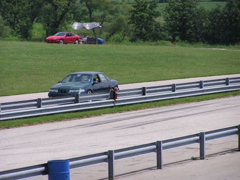 1993 Ford Taurus - A green 1993 Ford Taurus with racing number 98 is seen on the track, with another red car parked in the background.