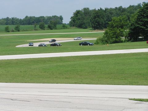 1993 Ford Taurus - Multiple cars are seen on a racetrack during a sunny day.