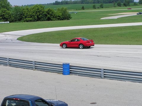 1993 Ford Taurus - Red coupe on race track with a blue pickup truck in the foreground.