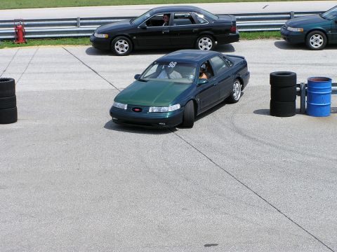 1993 Ford Taurus - A dark green Ford Taurus with a contrasting hood is on a track, with another Taurus in the background.