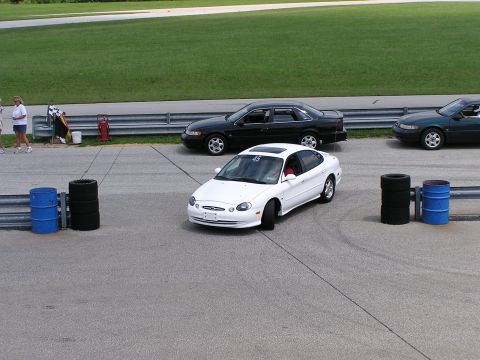 1993 Ford Taurus - A white Ford Taurus is on a race track with other cars visible in the background.