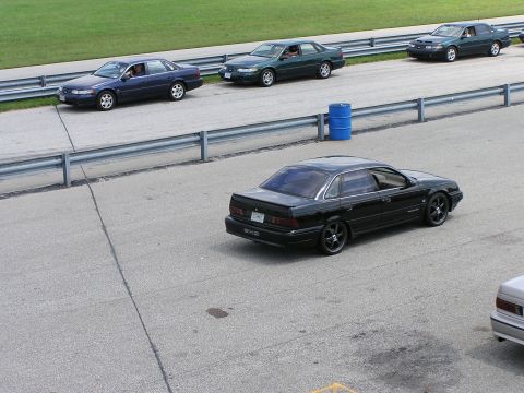 1993 Ford Taurus - Several sedans are on a racetrack, with a black sedan in the foreground.