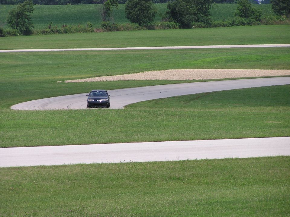 Dark sedan on a race track, front view