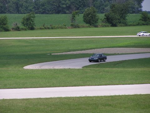 1993 Ford Taurus - Two cars on a race track, one in the foreground and another further back.