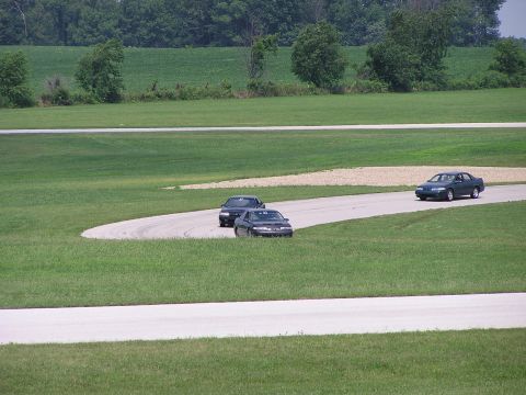 1993 Ford Taurus - A 1993 Ford Taurus navigates a turn on a race track, with two other sedans visible in the background.