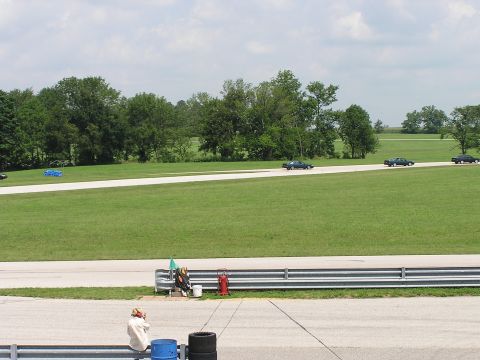 1993 Ford Taurus - Several cars are driving on a race track on a cloudy day.
