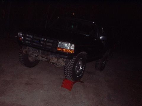 1993 Ford Bronco - This black Ford Bronco is parked at night with a red chock under its front tire.