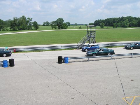 1993 Ford Taurus - A green 1993 Ford Taurus sedan drives on a racetrack next to other vehicles.