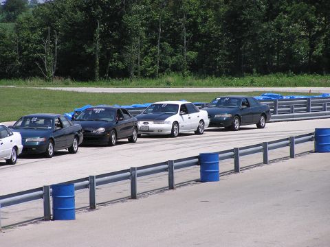 1993 Ford Taurus - Several Ford Taurus sedans are lined up on a racetrack, ready for an event.