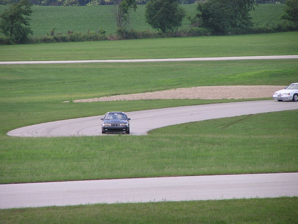 Dark 1993 Ford Taurus on race track, white car in background