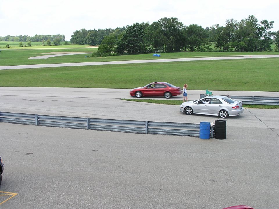 Silver sedan with a spoiler and a red sedan on a racetrack