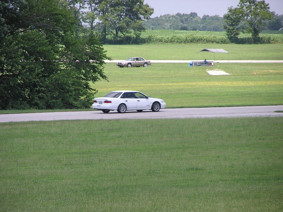 White 1993 Ford Taurus driving on a road, side view