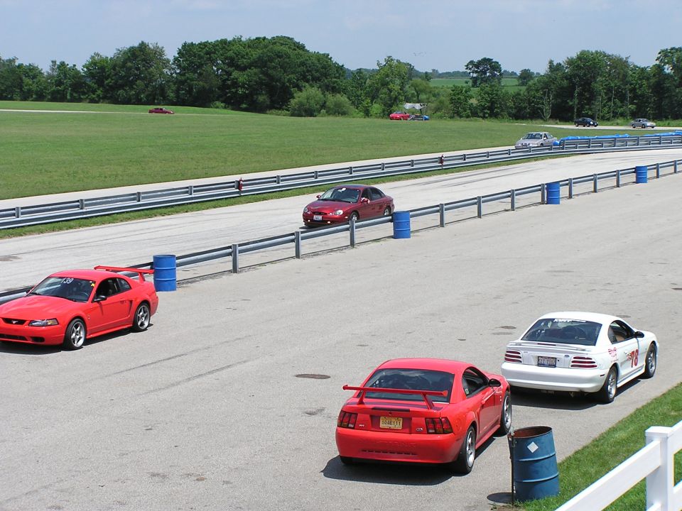 Red Ford Mustang with a large rear spoiler, seen from the rear
