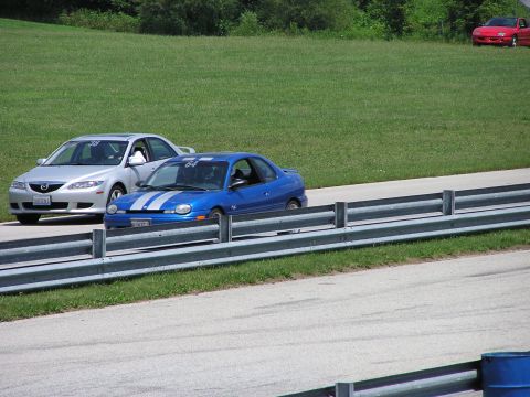 1993 Ford Taurus - Two cars race on a track, with a third car parked on the grass in the distance.