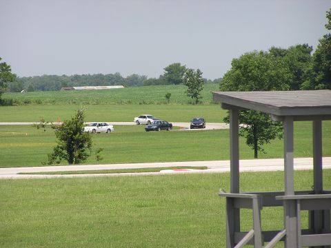 1993 Ford Taurus - Cars are seen driving on a track surrounded by green fields and trees under a hazy sky.