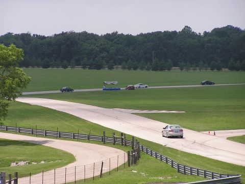 1993 Ford Taurus - Several cars are driving on a racetrack on a cloudy day.