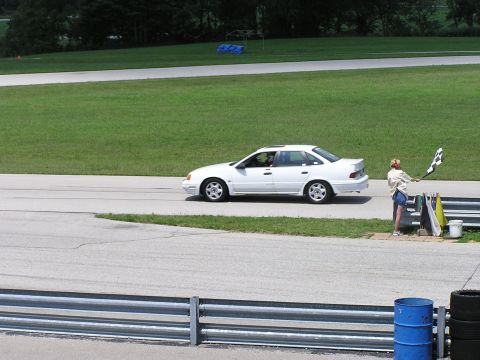 1993 Ford Taurus - White 1993 Ford Taurus on a race track, with a person waving a checkered flag.