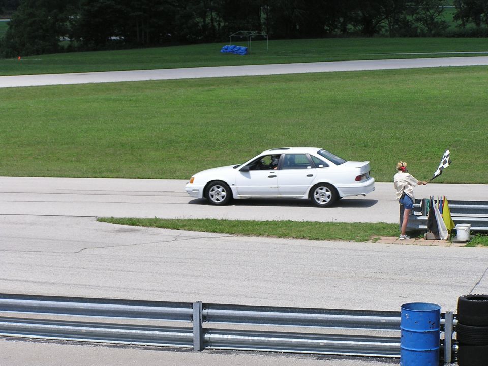 1993 Ford Taurus sedan on a race track, side view. Person with checkered flag nearby