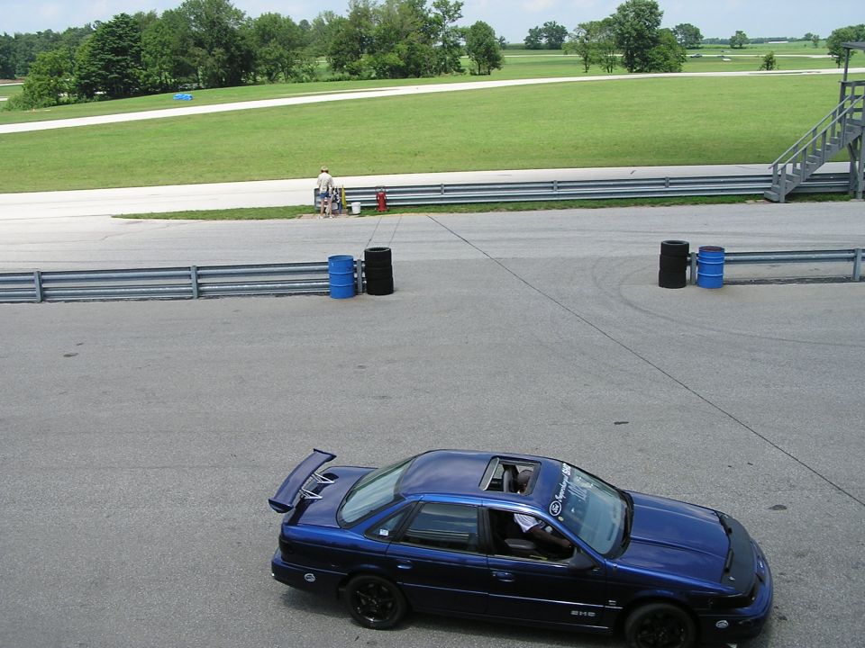 Blue 1993 Ford Taurus sedan with spoiler and sunroof on a racetrack