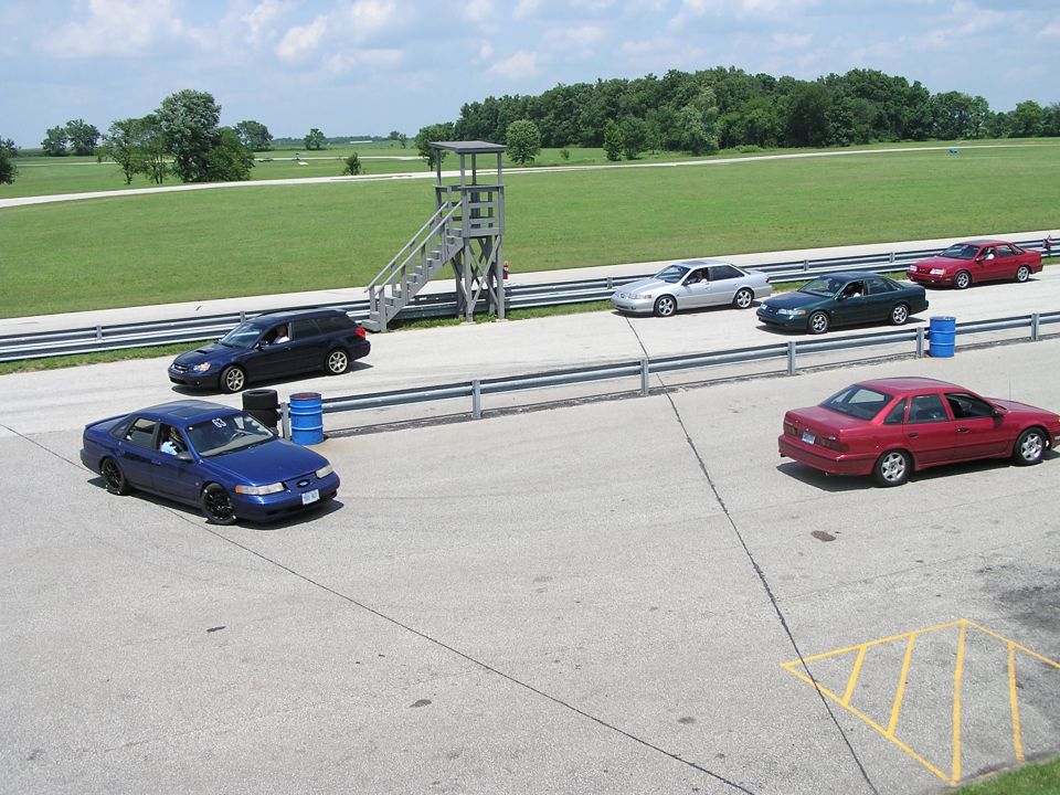 Blue 1993 Ford Taurus on a racetrack with other cars nearby