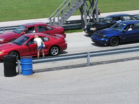 1993 Ford Taurus - Multiple Ford vehicles, including a red Mustang and three Tauruses, are lined up on a racetrack.