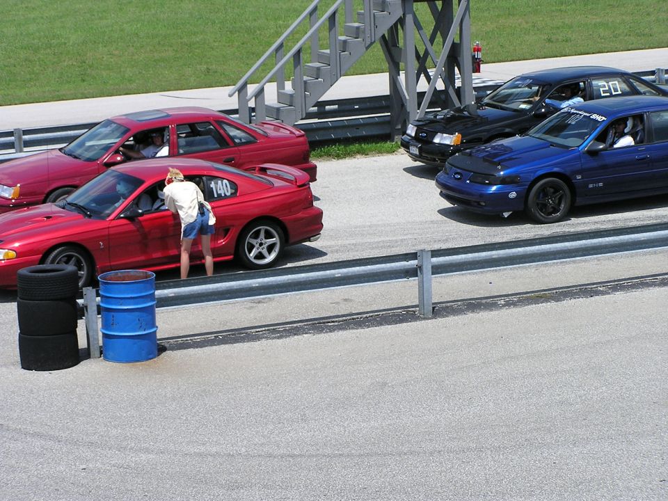 Red Ford Mustang with number 140, red Ford Taurus, blue Ford Taurus with number 20, and black Ford Taurus on a racetrack
