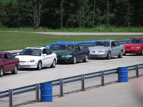 1993 Ford Taurus - Several Ford Taurus sedans, including a silver 1996 model with number 62, line up on a race track.