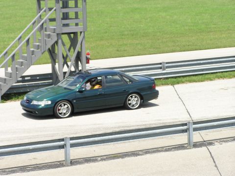 1993 Ford Taurus - A green sedan is seen on a racetrack, with a driver wearing a helmet visible inside.