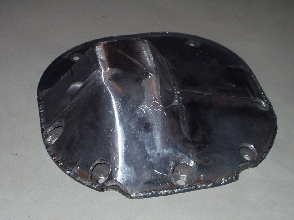 Welded steel differential cover with bolt holes on gray concrete